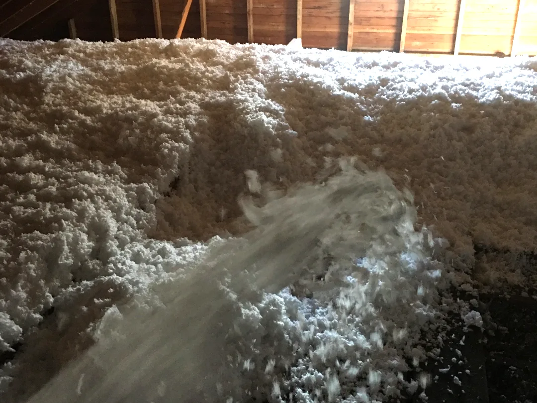 Blown-in insulation being installed across a Montana attic floor by Olympus Insulation