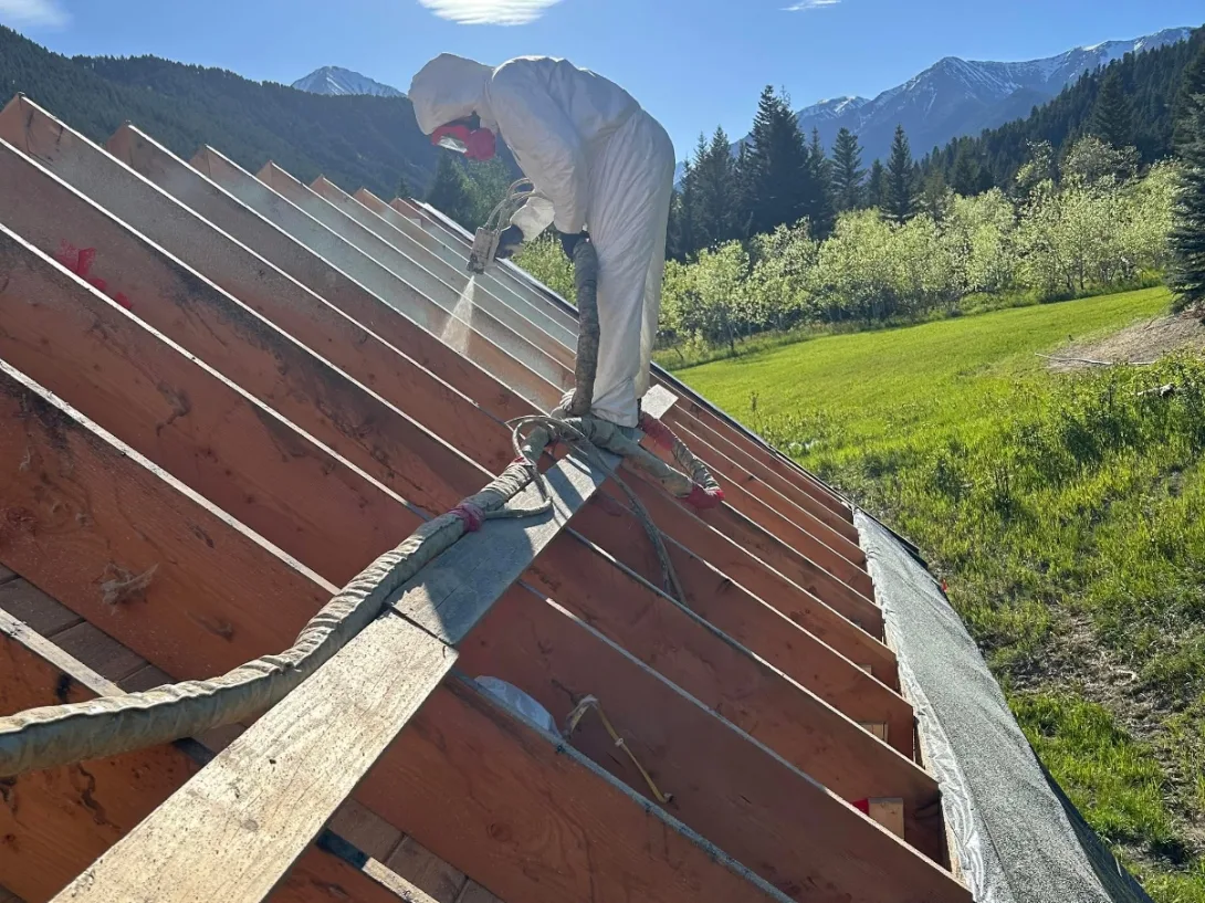 Olympus Insulation crew applying spray foam to a roofline in the Montana mountains