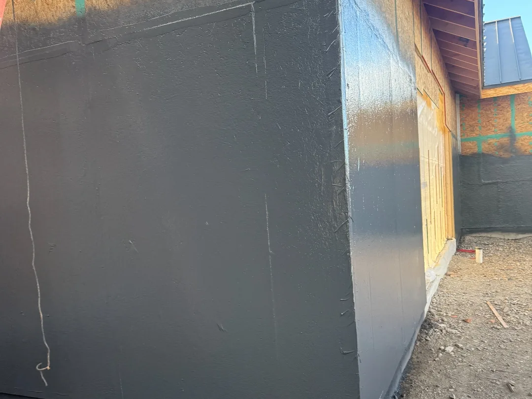 Seamless spray-applied waterproofing membrane wrapping a foundation corner on a Montana new build